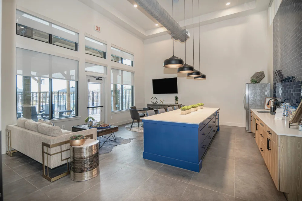 the kitchen has a blue island and a large window at The parcHAUS at Celina Parkway